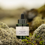 Bottle of ANGAN serum on a mossy background